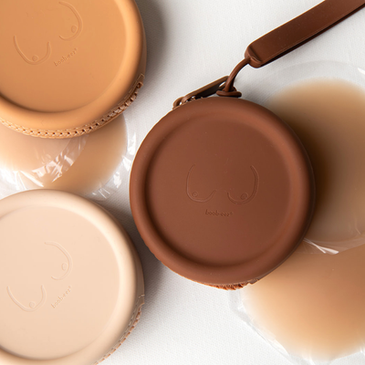 Product shot of reusable Silicone Travel Cases for Headlight Hiders in Light Nude, Medium Nude and Dark Nude, with Headlight Hiders laying underneath the Silicone Travel Cases, against a white background